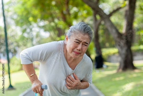 A woman in a white shirt is holding a cane and appears to be in pain. She is looking down at her chest, which is covered in a red rash
