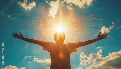 The photo shows a person standing with their arms outstretched in front of a bright light photo