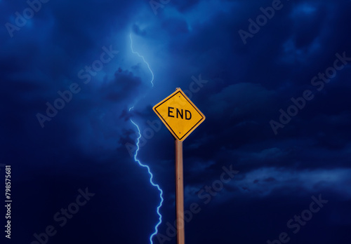 Yellow diamond shaped traffic sign with the word End written on it against a stormy cloudy sky with lightning and a blue toned sky