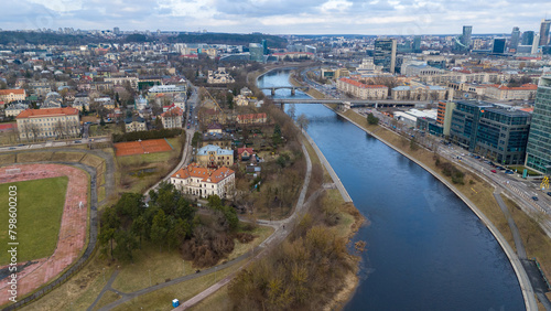 Drone photography of river shoreline going through city and people walking during spring day © M