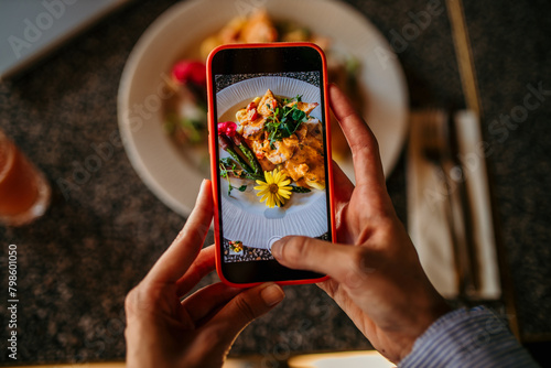 Woman taking photo of fine dining meal with smartphone