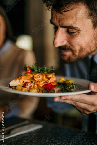 Handsome Young Man Enjoying the Aroma of a Meal in a Reastaurant