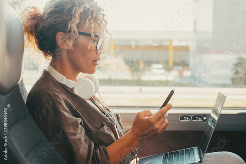 Businesswoman traveling on bus transport service transfer and writing message on mobile phone. One modern woman reading notification on cellphone sitting inside a bus vehicle. Travel and job lifestyle photo