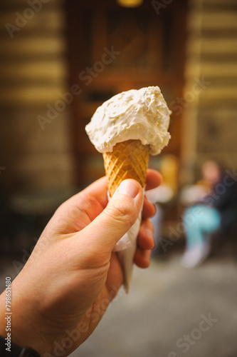 A close up shot of an italian artisanal ice cream cone and a hand holding it.