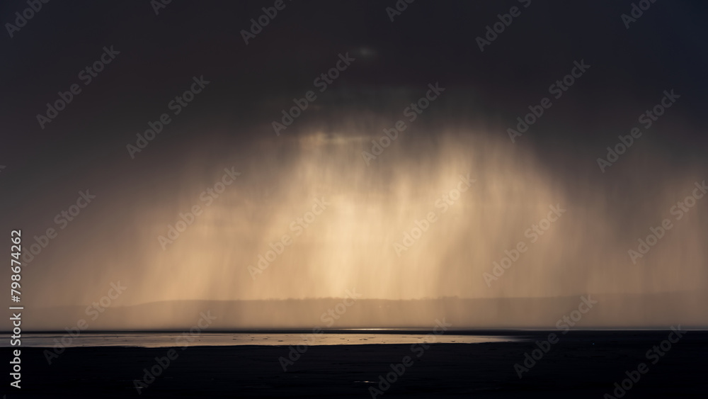 Beautiful moody storm skies over ocean landscape with distant heavy rainfall