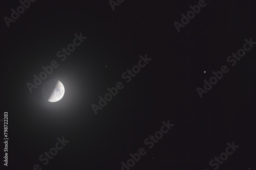 The mineral Moon in its first quarter phase, in conjunction with the star Pollux in the Gemini constellation and some background stars. You can see the earth-shine in the shadowed part.
