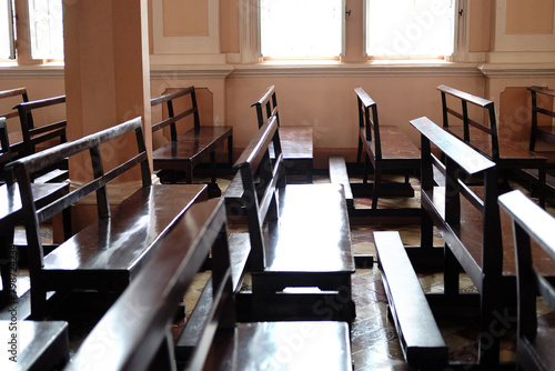 Vintage long wooden chairs for sitting and praying for blessings in Christian churches. Rows of church benches in sunlight 