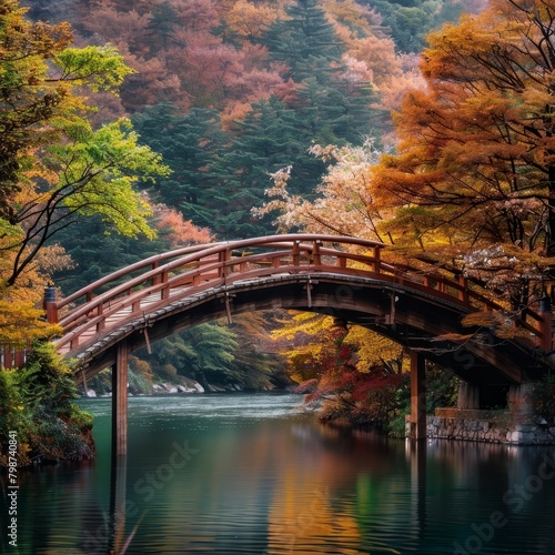 Autumn Wonderland:A Peaceful Wooden Bridge Arching over a Tranquil River Surrounded by the Vibrant Colors of a Lush Forest © kittipoj