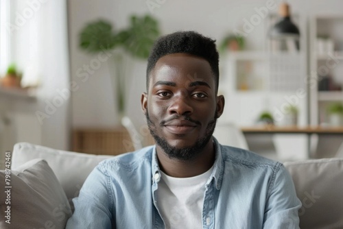 Person Looking At Camera. Millennial Guy Sitting on Sofa in Apartment Making Video Call for Blog