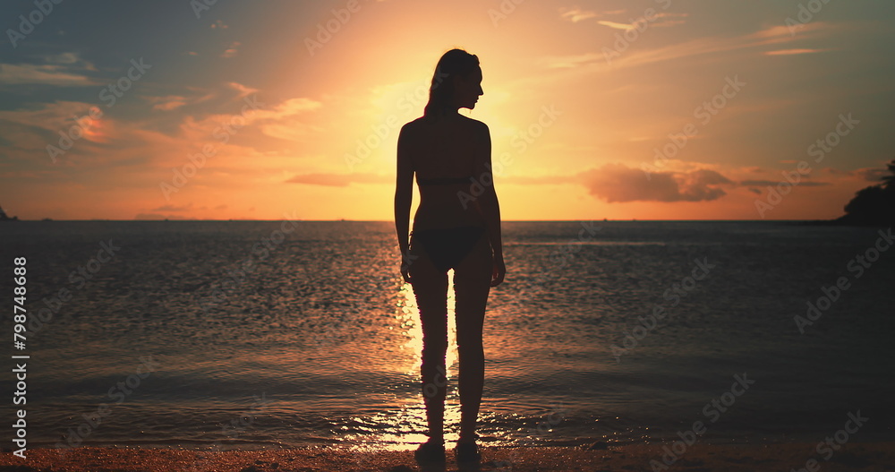Woman stands on Koh Ma Beach at Koh Phangan Island in Thailand during sunset, with the sky painted in warm hues and gentle waves breaking on the shore. Woman stands on Koh Ma Beach at Koh Phangan Island in Thailand during sunset, with the sky painted in warm hues and gentle waves breaking on the shore.