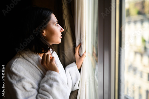 Thoughtful woman gazing out of window in soft light