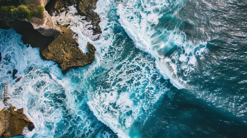 Aerial view of ocean waves colliding with a rocky shore background