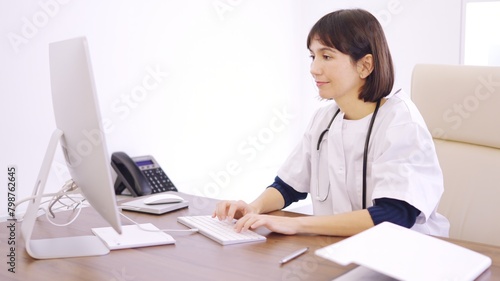 Doctor using computer sitting on a desk in a clinic