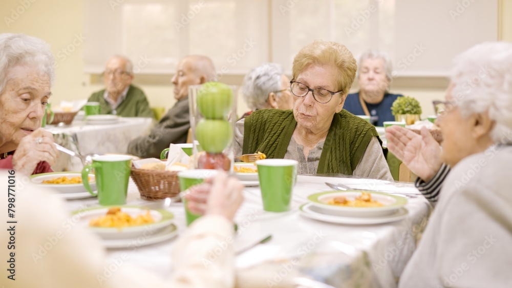 Senior women eating and talking sitting in geriatric's dinning room
