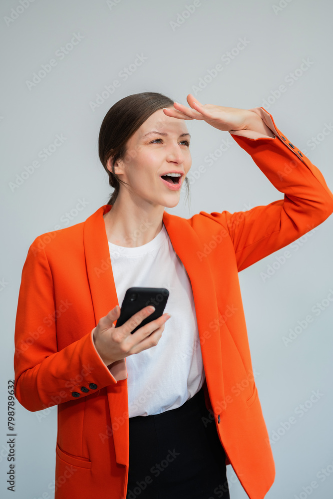 Naklejka premium Portrait of woman standing holding smartphone mugand looking outside, isolated on background.