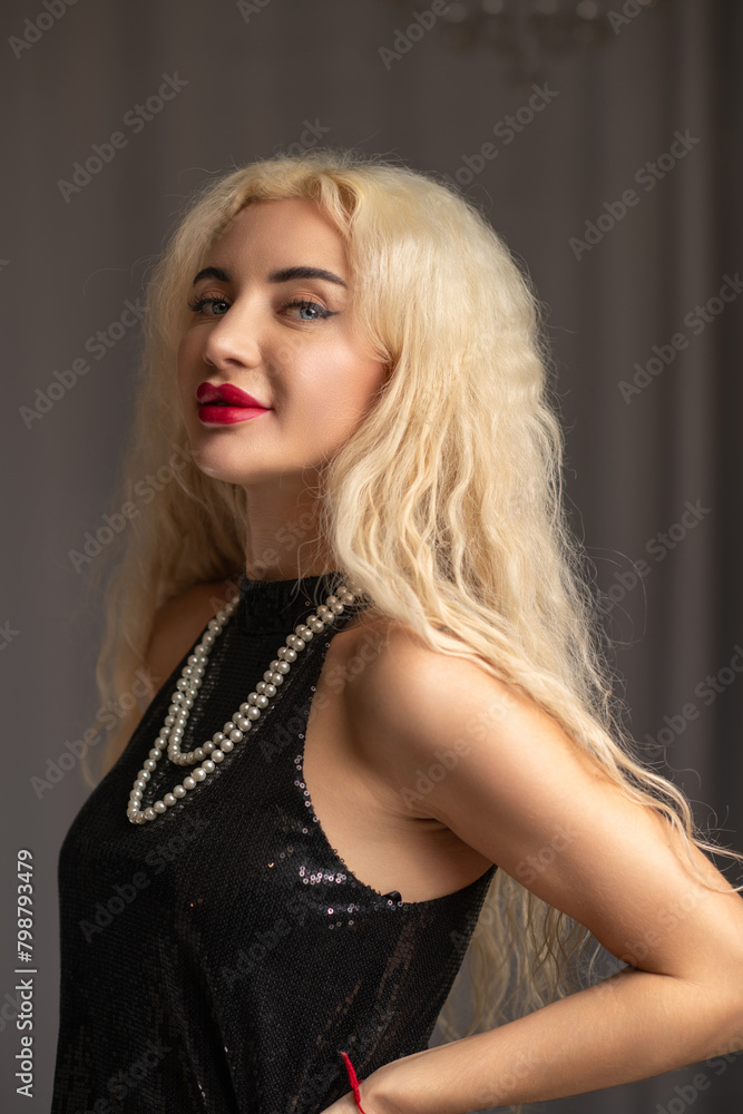 Portrait of a young beautiful blonde girl in a black dress in the studio. Portrait of a young beautiful blonde girl in a black dress in the studio.