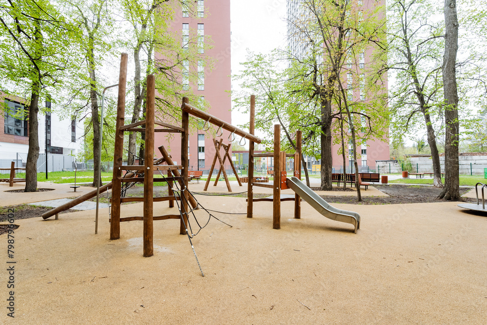 Wooden playground with slide and swings amidst park greenery for urban leisure Wooden playground with slide and swings amidst park greenery for urban leisure