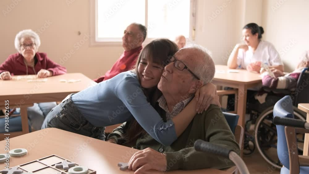 Smiling young woman hugging elderly man in retirement home Smiling young woman hugging elderly man in retirement home