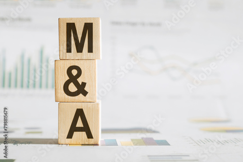M and A text on a wooden block on graph background