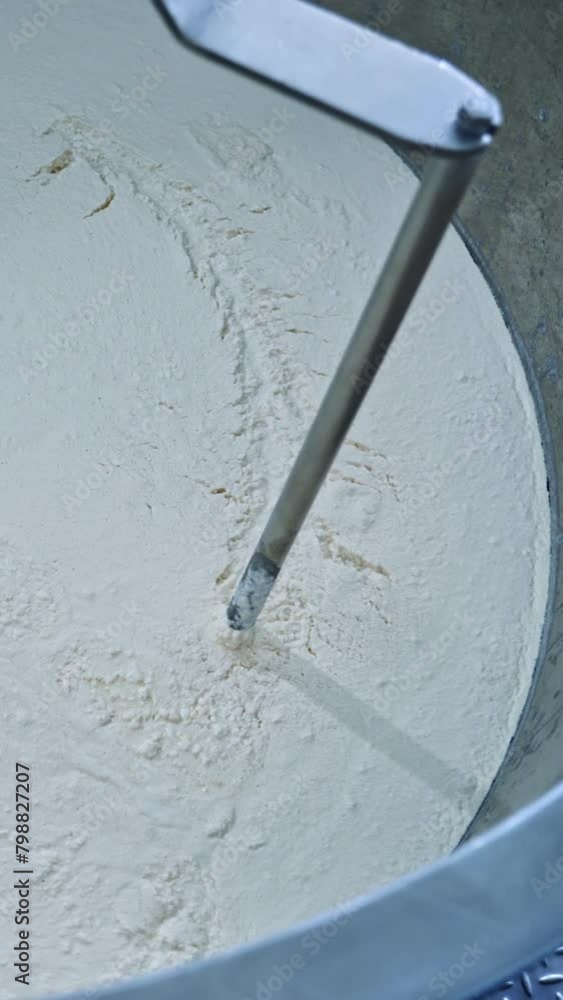 Slow motion of mixer in metal bowl for making cheese. Factory equipment. Metal mixing apparatus boils and mix milk for making cheese at milk products making factory. Vertical video Slow motion of mixer in metal bowl for making cheese. Factory equipment. Metal mixing apparatus boils and mix milk for making cheese at milk products making factory. Vertical video