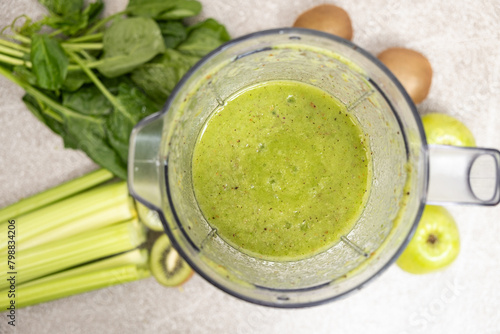 Making a green smoothie with celery  kiwi  apple and spinach in a blender  top view.