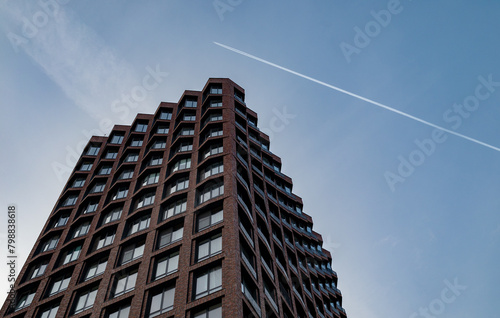 A trace of a passing plane over a modern multi-storey business class building.