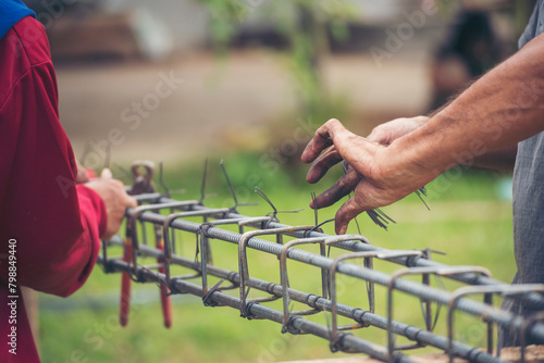 Construction Worker hands using pincer pliers iron wire. Outdoor Worker using wire bending pliers, construction work. Men hands bending cutting steel wire fences bar reinforcement of concrete work photo