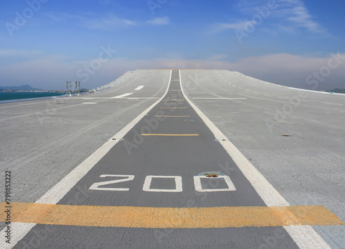 Tarmac runway track on deck of aircraft carrier with blue sky