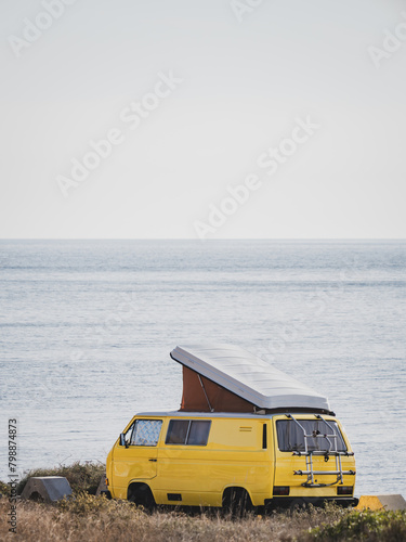 Vintage yellow camper van with pop-up roof by the sea