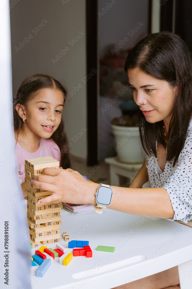 Fototapeta premium International Children Day. Beautiful Latino children playing with blocks on a white table. Playful, fun and thinking games. Happy children at home.