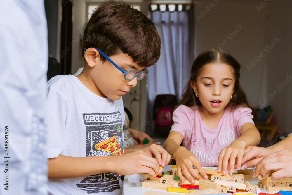 International Children Day. Beautiful Latino children playing with blocks on a white table. Playful, fun and thinking games. Happy children at home. International Children Day. Beautiful Latino children playing with blocks on a white table. Playful, fun and thinking games. Happy children at home.