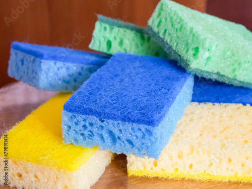 Vibrant Cleaning Sponges. A stack of blue, yellow, and green sponges. Uses for Cleaning product ads, household blogs.