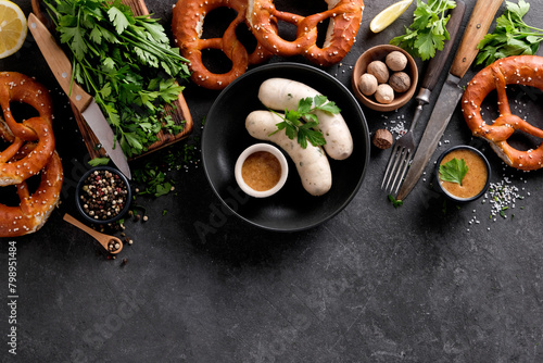 Bavarian white sausages with mustard and pretzel on a black background with copy space.