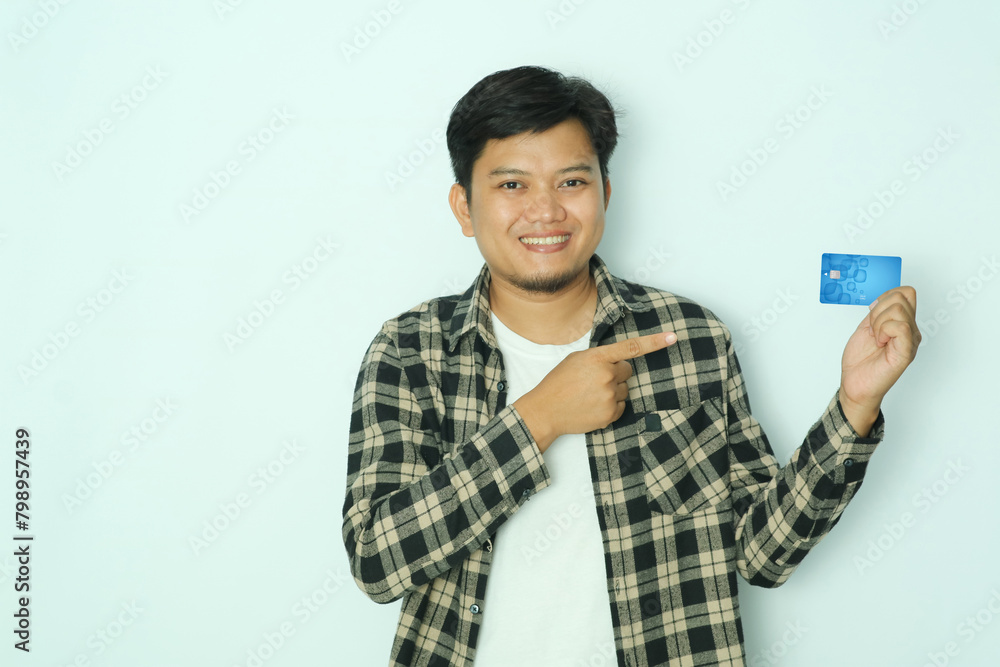Young Asian man smiling confident while right hand pointing to credit card that he hold Young Asian man smiling confident while right hand pointing to credit card that he hold