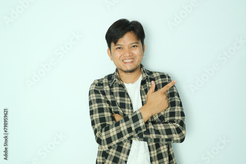 Young Asian man showing pointing finger to the left with smiling face