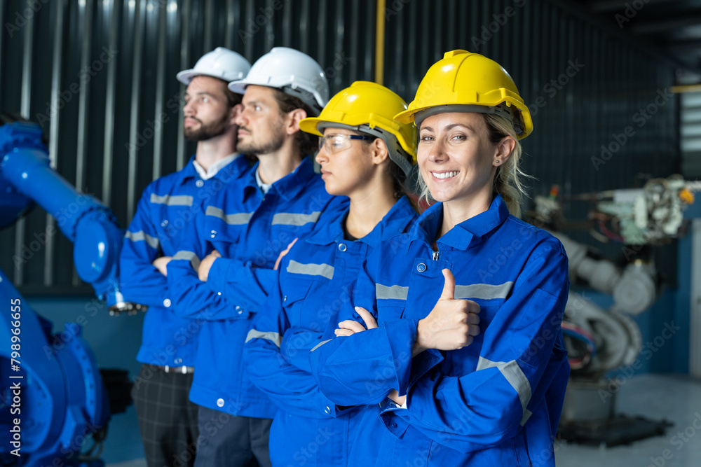 Group of robotic engineers wear helmets safety standing and arms crossed at factory workshop. Technician professional team robot arm welding machine. Group of robotic engineers wear helmets safety standing and arms crossed at factory workshop. Technician professional team robot arm welding machine.