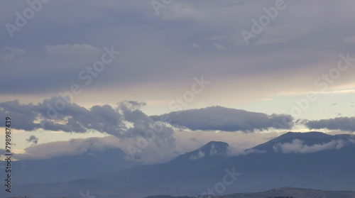 Nuvole bianche e grigie aggrappate come ovatta alle montagne in una giornata invernale al tramonto