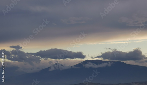Nuvole bianche e grigie aggrappate come ovatta alle montagne in una giornata invernale al tramonto photo