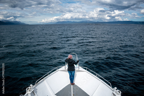Mujer parada en la proa de un barco mientras disfruta de su excursión de navegación por el canal de Beagle