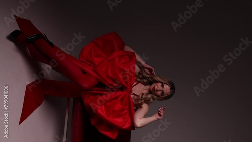 Caucasian woman in red, seated, modern chair, copy space. Concept for high-end fashion editorials or sophisticated interior design promotions. photo