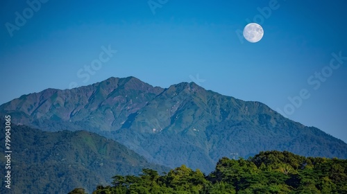  A mountain range backdropped by a full moon in the center of the sky, with trees in the foreground
