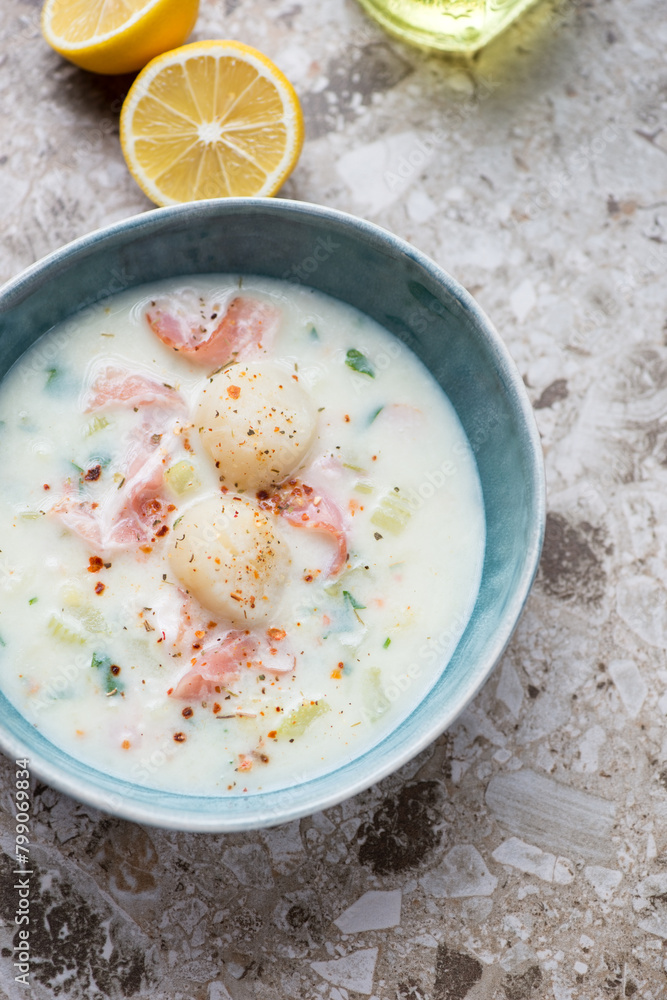 Green bowl with scallop chowder on a light-brown granite background, vertical shot, high angle view Green bowl with scallop chowder on a light-brown granite background, vertical shot, high angle view