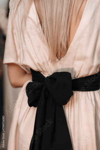 Beige elegant feminine fashion details spring summer dress with big black bow at the back.