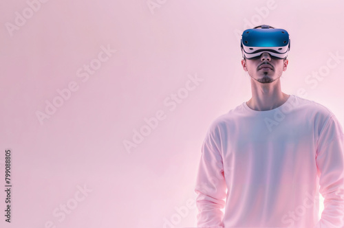 A man wears a virtual reality headset, immersed in a digital experience. Pink background copy space