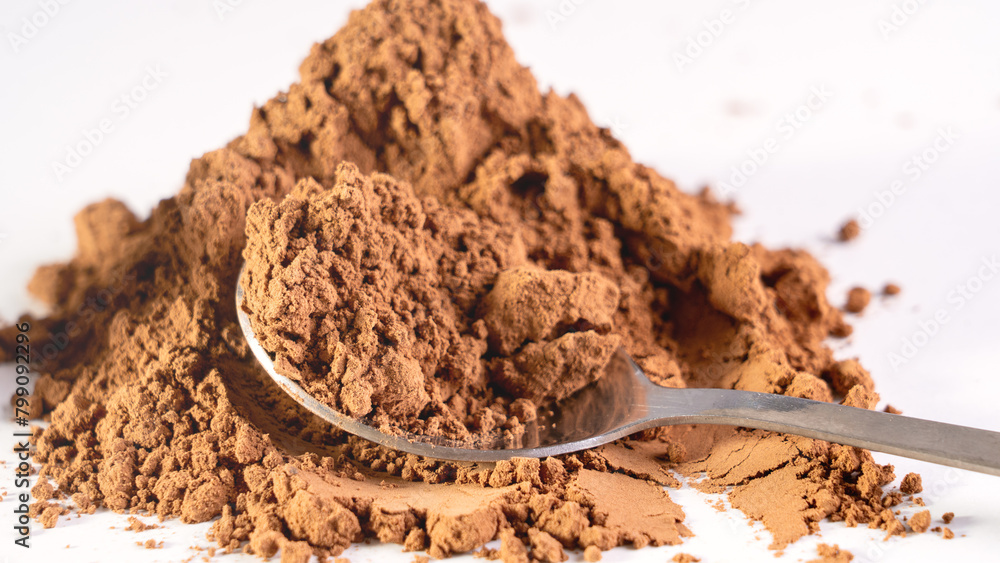 A spoon in cocoa powder in close-up. Cocoa is on the table and a spoon is poured. A spoon in cocoa powder in close-up. Cocoa is on the table and a spoon is poured.