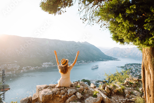 Young woman is looking at landscape of city from height. Travel in Europe. Back view.