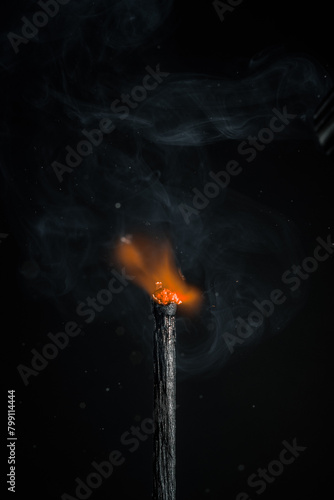 ignition of a black match on a black background. open fire, vertical photo with space for text