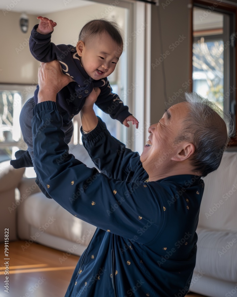 A Korean elderly grandfather plays joyfully with his little grandson in the living room on International Father's Day A Korean elderly grandfather plays joyfully with his little grandson in the living room on International Father's Day