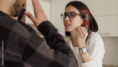 Young woman arguing heatedly with a young man and actively gesticulating their hands in the kitchen at home, close up during a quarrel in the relationship of a couple