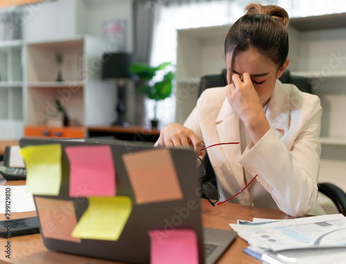 Stress business woman busy and pain from overwork. young adult Asian professional manager having office syndrome at office. beautiful employee upset in pain because working too much overtime work